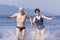 Beautiful mature couple runs on the water along the wild beach