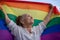 Beautiful mature senior woman with charming smile holding rainbow LGBT flag in her hands, gay and lesbian rights concept