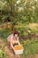 Beautiful mature women sits under an apricot tree with a large plastic container full of apricots