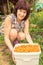 Beautiful mature women sits under an apricot tree with a large plastic container full of apricots