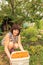 Beautiful mature women sits under an apricot tree with a large plastic container full of apricots