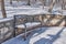 Beautiful melted snow covered bench with openwork patterns and silhouette of Pushkin`s head in the Zheleznovodsk Park, Russia