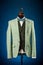 Beautiful men`s green jacket suit with vest, shirt and bow tie on a dummy or mannequin on blue background