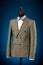 Beautiful men`s grey jacket suit with shirt and tie on a dummy or mannequin on blue background