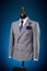 Beautiful men`s grey jacket suit with shirt and tie on a dummy or mannequin on blue background