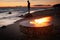 The beautiful metal round a fireplace stands on the sandy coast with a tidal wave at sunset, stones, sand, waves, the