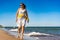 Beautiful mid adult woman walking, running on sunny beach