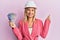 Beautiful middle age blonde woman wearing architect hardhat holding indian rupee smiling happy pointing with hand and finger to