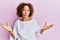 Beautiful middle age mature woman wearing elegant clothes over pink background clueless and confused expression with arms and
