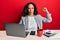 Beautiful middle age woman working at the office drinking a cup of coffee strong person showing arm muscle, confident and proud of