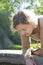 Beautiful middle-aged blonde woman bent over and leaning on the edge of a water well and looking inside