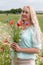 beautiful middle-aged blonde woman stands among a flowering field of poppies