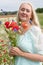 beautiful middle-aged blonde woman stands among a flowering field of poppies