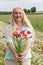 beautiful middle-aged blonde woman stands among a flowering field of poppies