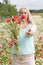 beautiful middle-aged blonde woman stands among a flowering field of poppies