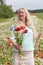 beautiful middle-aged blonde woman stands among a flowering field of poppies