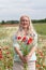 beautiful middle-aged blonde woman stands among a flowering field of poppies