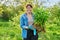 Beautiful middle aged woman with rooted phlox paniculata plant looking at camera