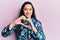 Beautiful middle eastern woman wearing casual floral jacket smiling in love doing heart symbol shape with hands