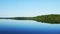 Beautiful Minnesota lake with reflection of distant shoreline with forest and blue sky in early morning light in panning clip.