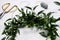 Beautiful mistletoe wreath and florist supplies on white wooden table. Traditional Christmas decor