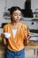 Beautiful mixed race girl in orange shirt holding cup of coffee and croissant in morning