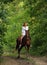 Beautiful model girl rides with horse in woods road in evening down