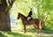 Beautiful model girl rides with horse in woods road in evening down