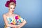 Beautiful model with updo hair and perfect bright make up wearing colorful open shoulder dress with floral print and peony garland
