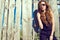 Beautiful model wearing black jumpsuit and trendy aviator sunglasses standing at the old shabby fence made of boards