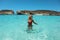 Beautiful model woman in red bikini relaxing in blue lagoon,standing in azure water smiling,enjoying vacation and traveling