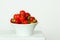 A beautiful modern bowl from white porcelain filled with fresh and tasty strawberries  in front of a white background