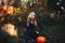 Beautiful modern witch holding halloween pumpkin in the forest. october. happy holidays