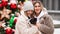 Beautiful mom and daughter with dog Papillon near Christmas tree on street.