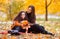 Beautiful mom and daughter teenager on a walk in the fall. A child in orange jacket, a woman in black clothes. They are sitting on