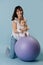 Beautiful mom does charging with baby on fitness ball