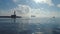 Beautiful morning over the shining sea waves. Lighthouse and sailing boat, view toward horizon.