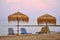 Beautiful morning - sunset and parasols and deck chairs on the beach by the sea.