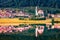 Beautiful morning view of Parrocchia di San Lucano Vescovo Catholic Church. Calm summer scene of Santa Caterina lake and Auronzo d