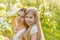 Beautiful mother and daughter in a blooming garden in the spring