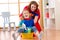 Beautiful mother and her cute little daughter dressed like superheroes cleaning and playing