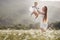 Beautiful mother and her daughter playing in spring flower field