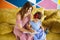 Beautiful mother with her little cute daughter in blue dress learning to write with felt tip pens in notepad together on