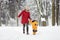 Beautiful mother and his son walking in winter park during snowfall