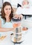 Beautiful mother mixing carrot with a blender