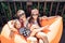 Beautiful mother with two daughters sitting on an orange lounge