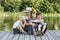 Beautiful mother with two young sons are embracing on the pier on the river bank