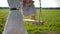 A beautiful mother in a white dress helps her daughter to sit on a wooden hanging rope swing.