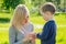 Beautiful mother wipes hands with napkins of cute baby son in the park on a background of green grass and trees