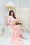 Beautiful motherhood. Pregnant in tender peach dress sits on chair